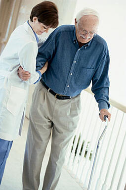 Older man with a cane being helped by a doctor