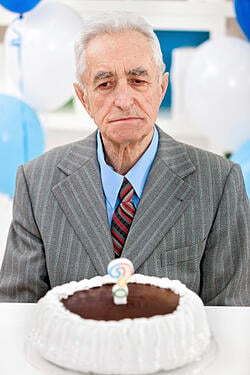Elderly man and a birthday cake topped with a question mark