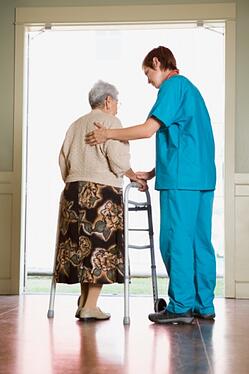 Elderly nursing home resident standing with a nurse