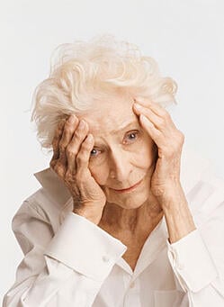Unhappy elderly woman with her head in her hands